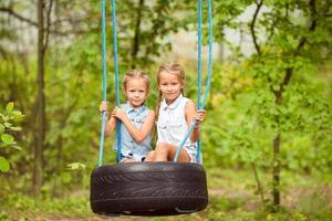 adorabile poco ragazze avendo divertimento su un' swing all'aperto foto