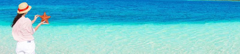 panorama di giovane donna con stella marina su bianca spiaggia nel il natura Riserva foto