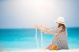 donna posa su il spiaggia godendo estate vacanze guardare a il mare foto