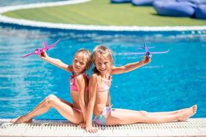 bellissimo poco ragazze avendo divertimento vicino un all'aperto piscina foto