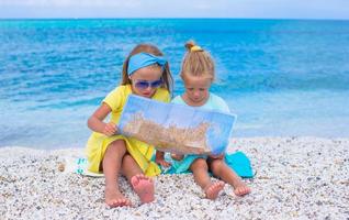 adorabile poco ragazze con carta geografica di isola su tropicale spiaggia foto