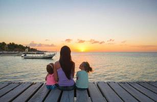 mamma e poco figlie silhouette nel il tramonto su il ponte foto