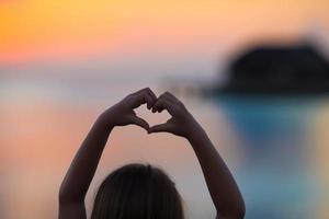 silhouette di cuore fatto di bambini mano a tramonto foto