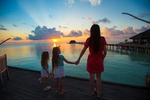 silhouette di giovane madre e Due sua poco ragazze a tramonto foto