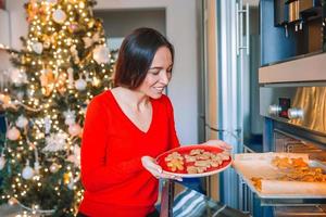 giovane donna nel Natale cappello cottura al forno Pan di zenzero a casa. foto