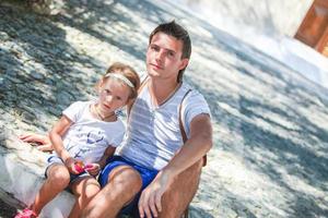 giovane padre con poco figlie avere un' riposo su strada nel vecchio greco cittadina foto