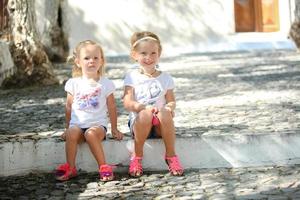 poco carino sorelle seduta a strada nel vecchio greco villaggio di emporio, santorini foto