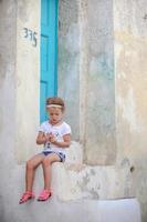 adorabile poco ragazza seduta su il passaggi di vecchio Casa nel emporio villaggio, santorini, Grecia foto