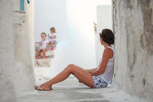 giovane madre sfondo sua caro figlie nel un' greco villaggio su il Cicladi isole foto