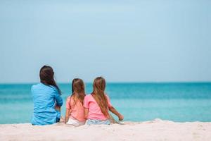 adorabili bambine e giovane madre sulla spiaggia bianca foto