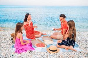 famiglia avendo un' picnic su il spiaggia foto