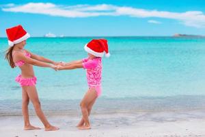 poco adorabile ragazze nel Santa cappelli durante spiaggia vacanza avere divertimento insieme foto