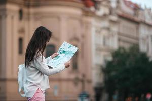 contento giovane donna con un' città carta geografica nel città. viaggio turista donna con carta geografica nel praga all'aperto durante vacanze nel Europa. foto