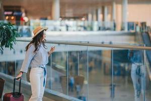 giovane donna nel cappello con Bagaglio nel internazionale aeroporto. foto