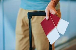 primo piano dell'uomo che tiene i passaporti e la carta d'imbarco all'aeroporto foto