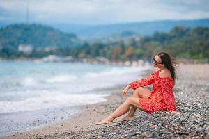 giovane contento donna su il spiaggia con montagna Visualizza foto