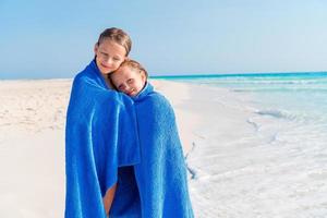 poco ragazze avendo divertimento in esecuzione con asciugamano e godendo vacanza su tropicale spiaggia foto