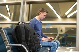 giovane uomo con il computer portatile e bagaglio a aeroporto foto