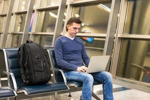 giovane uomo con il computer portatile e zaino a aeroporto foto