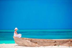 adorabile poco ragazza su vecchio barca a bianca spiaggia foto