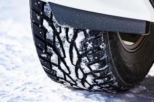 avvicinamento tiro di automobile costellato pneumatico coperto con neve a inverno nevoso strada foto