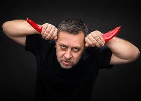 anziano uomo Tenere Due rosso caldo chili peperoni foto