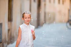 poco ragazza soffiaggio sapone bolle nel europeo città. ritratto di caucasico ragazzo godere estate vacanza nel Italia foto