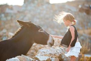 poco ragazza con asino su il isola di mykonos foto