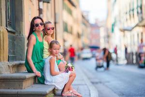contento madre e poco adorabile ragazze su accogliente strada durante italiano vacanza. famiglia europeo vacanza. foto
