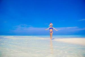 contento poco ragazza nel Santa cappello su il spiaggia durante vacanza foto