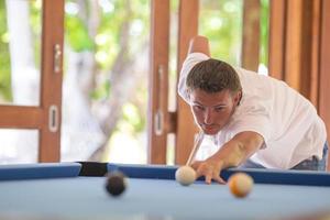 giovane uomo giocando biliardo su estate vacanza foto