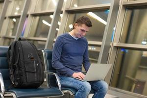 uomo d'affari utilizzando il computer portatile o taccuino computer mentre seduta su il sedia a il aeroporto foto