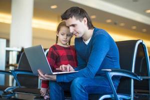 padre e poco ragazza con il computer portatile a il aeroporto mentre in attesa il suo volo foto