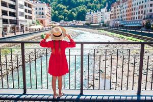 poco ragazza a cappello su il argine di un' montagna fiume nel un' europeo città. foto