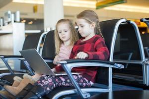 bambini con un' il computer portatile a il aeroporto mentre in attesa il suo volo foto