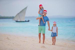 contento famiglia nel Santa cappelli su estate vacanza. Natale vacanze con giovane famiglia di quattro godendo loro mare viaggio foto