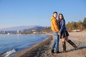 giovane coppia a piedi a il spiaggia su un' soleggiato inverno giorno foto