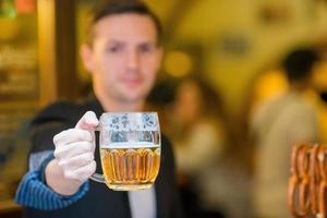 giovane uomo con birra e salato morbido salatini nel birra sport bar foto