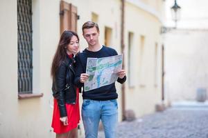 giovane coppia in viaggio su vacanze all'aperto sorridente contento. caucasico famiglia con città carta geografica nel ricerca di attrazioni foto