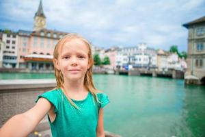 adorabile poco ragazza assunzione autoscatto all'aperto nel zurigo, Svizzera. avvicinamento ritratto di ragazzo sfondo di bellissimo città foto
