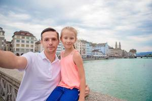 giovane papà e figlia assunzione autoscatto sfondo famoso fraumunster Chiesa e fiume limmat, Svizzera. foto