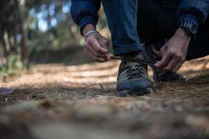 giovane escursionista allaccia i lacci delle scarpe mentre è in viaggio con lo zaino in spalla nella foresta foto