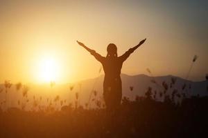 silhouette di una donna che prega su uno sfondo di cielo foto