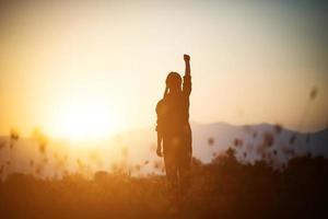 silhouette di una donna che prega su uno sfondo di cielo foto