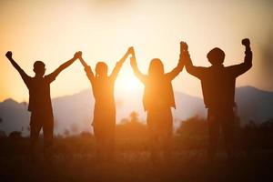 silhouette della squadra felice che unisce le mani in aria foto