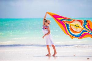 poco ragazza avere divertimento con spiaggia asciugamano durante tropicale vacanza foto