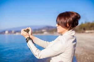 donna mani Tenere piccolo pietre modulo cuore forma sfondo il mare foto