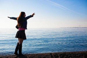 giovane bellissimo donna godendo il vacanza diffusione sua mani su spiaggia foto