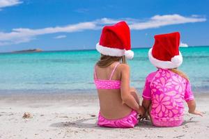 poco adorabile ragazze nel Santa cappelli durante loro spiaggia tropicale vacanza foto