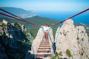 ragazze attraversamento il abisso su il corda ponte. foto